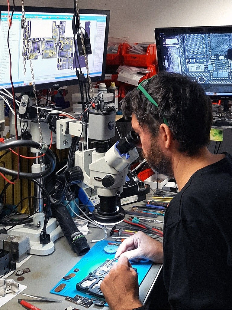 Un technicien Nous Globals répare une carte mère au microscope